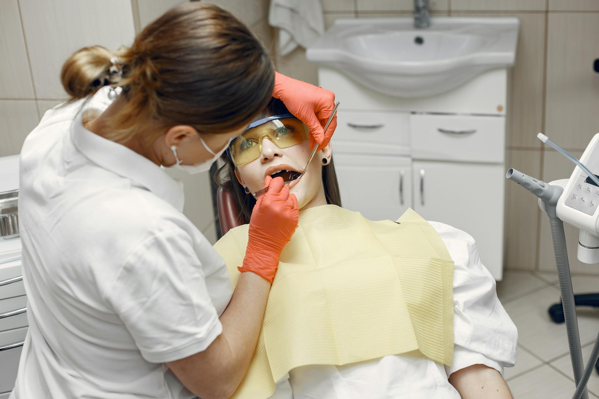 Professional dentist examines patient in a dental clinic with safety gear.